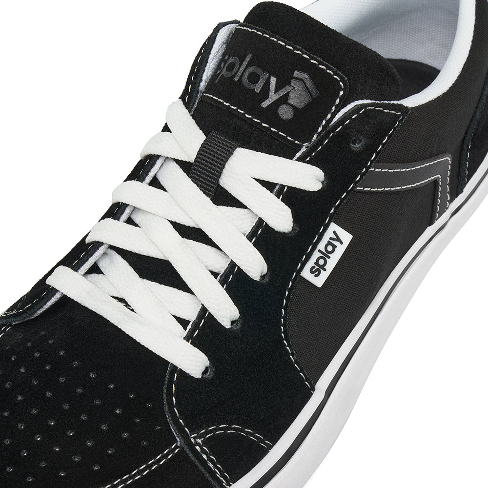 Close-up of the lace area of a black REV LTS Los Angeles sneaker showing contrast white stitching, laces, and tongue label with REV logo.